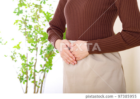 young woman with hands on lower abdomen 97385955