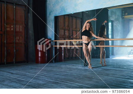 a beautiful girl of athletic build, a ballerina stands at a ballroom dancing machine in a large loft-style gym, a huge mirrored wall, daylight from the window a beautiful girl of athletic build, a ballerina stands at a ballroom dancing machine in a large loft-style gym, a huge mirrored wall, daylight from the window 97386054