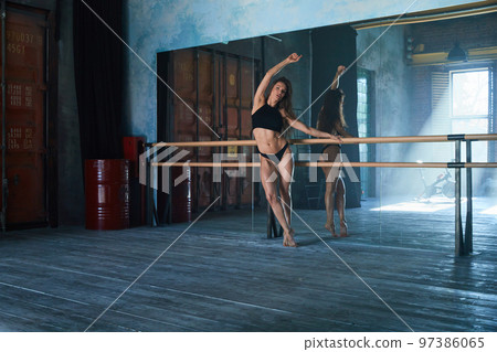 a beautiful girl of athletic build, a ballerina stands at a ballroom dancing machine in a large loft-style gym, a huge mirrored wall, daylight from the window a beautiful girl of athletic build, a ballerina stands at a ballroom dancing machine in a large loft-style gym, a huge mirrored wall, daylight from the window 97386065