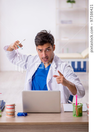 Young male dentist working in the clinic 97386421
