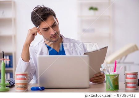 Young male dentist working in the clinic 97386432