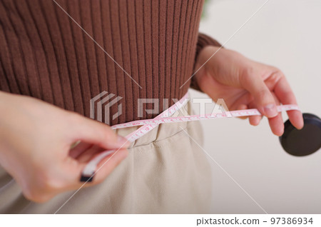 Woman measuring waist with measure 97386934