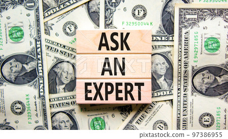 Ask an expert symbol. Concept words Ask an expert on wooden blocks on a beautiful background from dollar bills. Business and ask an expert concept. Copy space. 97386955
