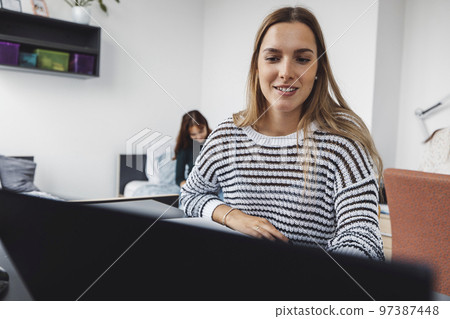 Smiling caucasian woman in stripy sweater doing work on her laptop 97387448