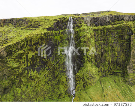 Moss covered rock wall and Drifandi waterfall - Iceland Moss covered rock wall and Drifandi waterfall - Iceland 97387583