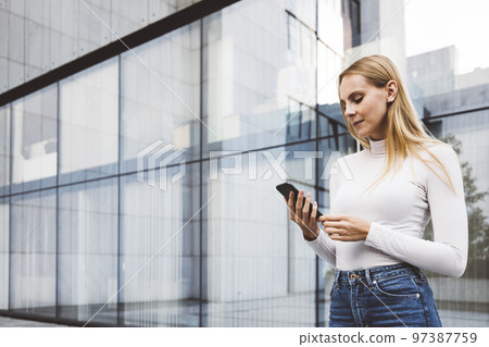 Waist up woman in urban setting standing outside looking at her phone Waist up woman in urban setting standing outside looking at her phone 97387759