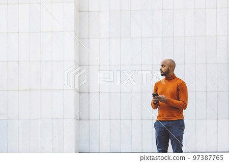 Man holding a phone standing outside the office building  97387765