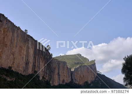 Mountain landscape, with trees and sky with clouds 97388274
