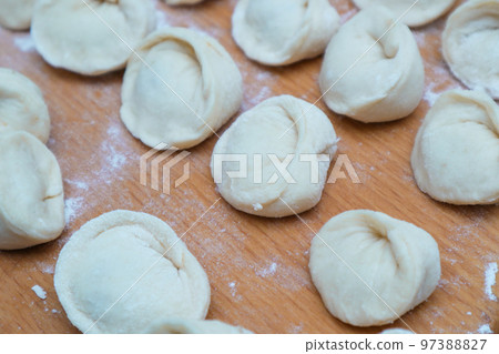 Dumplings with meat. Vareniki Homemade. Flour, dough on a wodden background. Home cooking dumplings, dough and minced meat Dumplings with meat. Vareniki Homemade. Flour, dough on a wodden background. Home cooking dumplings, dough and minced meat 97388827