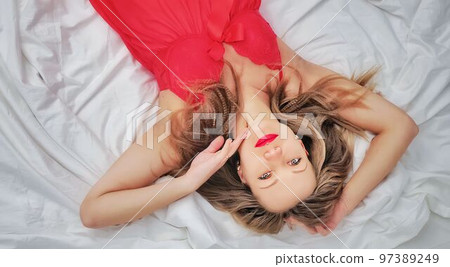 attractive girl in a red dress lies on the bed attractive girl in a red dress lies on the bed 97389249
