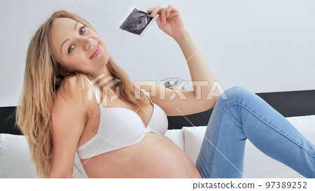 Ultrasound image pregnant baby photo. Woman holding ultrasound pregnancy picture. Pregnancy, medicine, pharmaceutics, health care and people concept 97389252