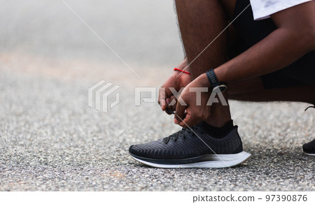 Close up Asian sport runner black man wear watch sitting he trying shoelace running shoes getting ready for jogging and run at the outdoor street health park, healthy exercise workout concept 97390876