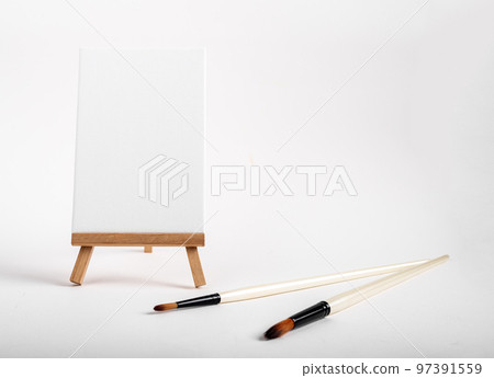 Canvas on tiny mini wood easel, blank mock up on wooden tripod, paintbrushes. Artistic supplies composition. High quality photo Canvas on tiny mini wood easel, blank mock up on wooden tripod, paintbrushes. Artistic supplies composition. High quality photo 97391559
