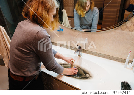 women with plunger and dirty sink with the clog in the pipe. 97392415