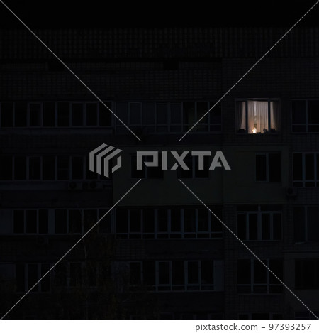 Light in one window in apartment multistorey building during the rolling blackout of electricity in a residential area of Kyiv after russian shelling. 97393257