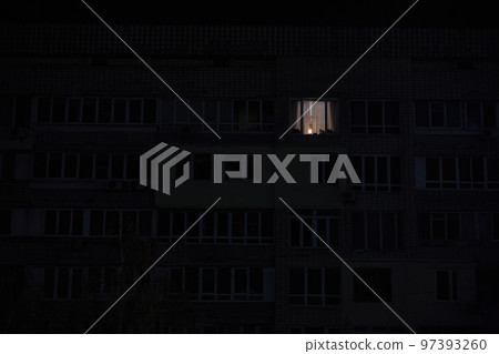 Light in one window in apartment multistorey building during the rolling blackout of electricity in a residential area of Kyiv after russian shelling. Light in one window in apartment multistorey building during the rolling blackout of electricity in a residential area of Kyiv after russian shelling. 97393260