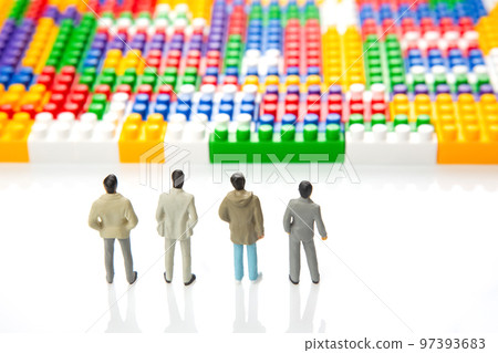 miniature people. figures of people stand near the colored plastic blocks 97393683