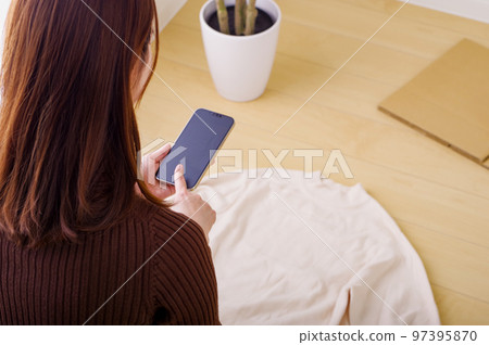 一個年輕女人在她的智能手機上賣跳蚤市場 一個年輕女人在她的智能手機上賣跳蚤市場 97395870