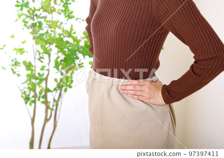 A woman putting her hand on her back A woman putting her hand on her back 97397411