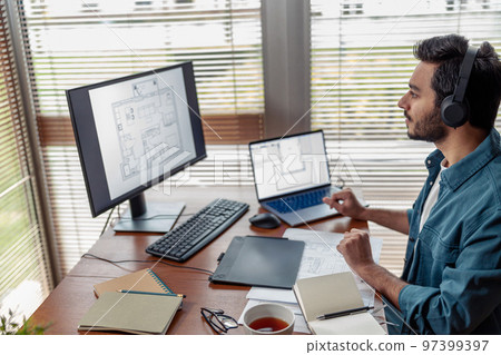 indian male designer in headphones works in home office drawing on graphic tablet indian male designer in headphones works in home office drawing on graphic tablet 97399397
