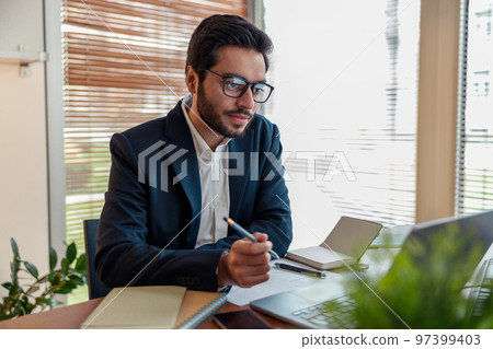 Focused indian businessman in suit working with documents from home office Focused indian businessman in suit working with documents from home office 97399403