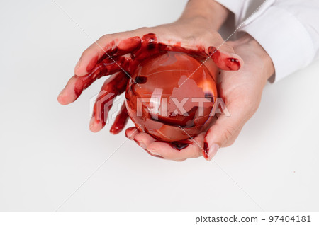 A woman holds a crystal globe smeared in blood on a white background. A woman holds a crystal globe smeared in blood on a white background. 97404181