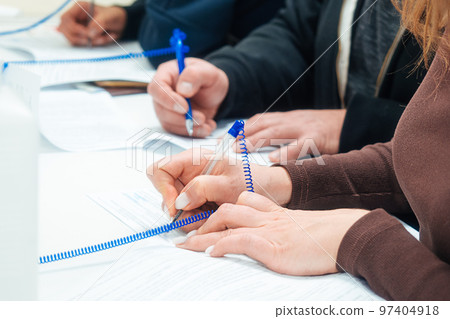 Woman fills out blank application form at table or signs contract. Hands of people with close-up Woman fills out blank application form at table or signs contract. Hands of people with close-up 97404918