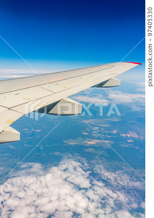View from the airplane window at a beautiful cloudy sky and the airplane wing 97405330