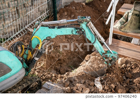 Mini excavator digs a trench to lay pipes. Close up of an excavator digging a deep trench. An excavator digs a trench in the countryside to lay a water pipe. Slow motion Mini excavator digs a trench to lay pipes. Close up of an excavator digging a deep trench. An excavator digs a trench in the countryside to lay a water pipe. Slow motion 97406240