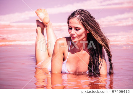 Young woman with long hair in pink salty lake with crystals of salt. Extremely salty pink lake, colored by microalgae with crystalline salt depositions. Spa, beauty and health care concept. Young woman with long hair in pink salty lake with crystals of salt. Extremely salty pink lake, colored by microalgae with crystalline salt depositions. Spa, beauty and health care concept. 97406415
