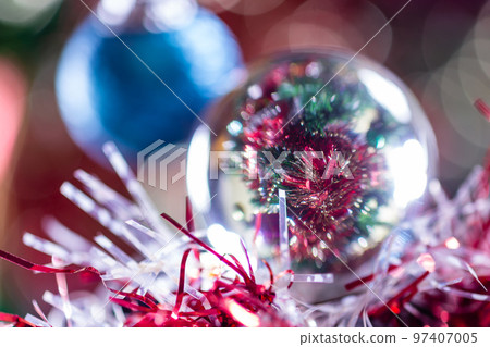 Close-up of Christmas decorations on a tree through lensball sphere Close-up of Christmas decorations on a tree through lensball sphere 97407005