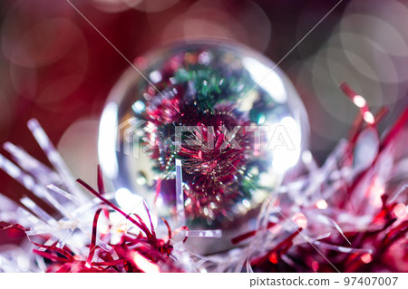 Close-up of Christmas decorations on a tree through lensball sphere Close-up of Christmas decorations on a tree through lensball sphere 97407007