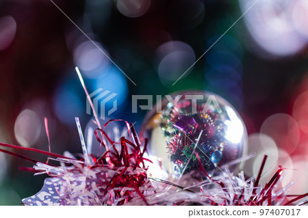 Close-up of Christmas decorations on a tree through lensball sphere Close-up of Christmas decorations on a tree through lensball sphere 97407017