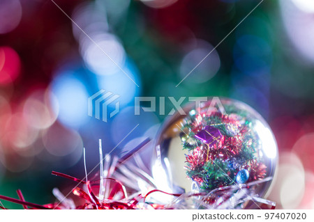 Close-up of Christmas decorations on a tree through lensball sphere Close-up of Christmas decorations on a tree through lensball sphere 97407020