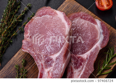 Fresh raw pork meat on the ribs with spices and herbs on a wooden cutting board 97408724