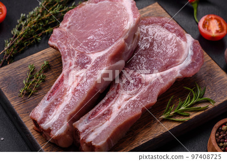 Fresh raw pork meat on the ribs with spices and herbs on a wooden cutting board 97408725