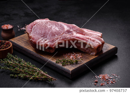 Fresh raw pork meat on the ribs with spices and herbs on a wooden cutting board Fresh raw pork meat on the ribs with spices and herbs on a wooden cutting board 97408737