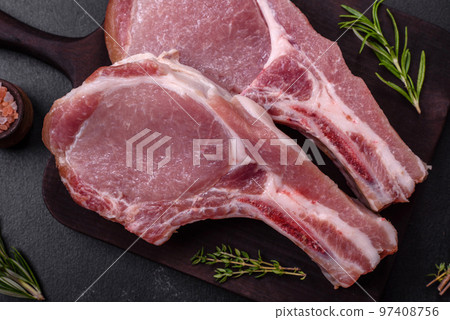 Fresh raw pork meat on the ribs with spices and herbs on a wooden cutting board Fresh raw pork meat on the ribs with spices and herbs on a wooden cutting board 97408756