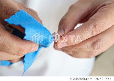 Jeweller hand polishing and cleaning jewelry diamond ring with micro fiber fabric Jeweller hand polishing and cleaning jewelry diamond ring with micro fiber fabric 97410637