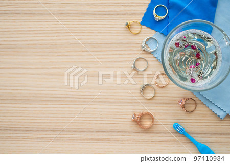cleaning jewelry diamond ring with glass of hot water and dishwashing liquid on wood table background cleaning jewelry diamond ring with glass of hot water and dishwashing liquid on wood table background 97410984