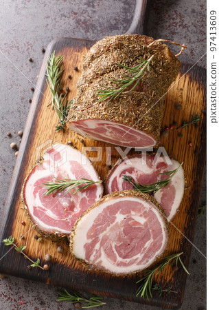 Closeup of a wooden board with slices of italian pancetta closeup. Vertical top view Closeup of a wooden board with slices of italian pancetta closeup. Vertical top view 97413609