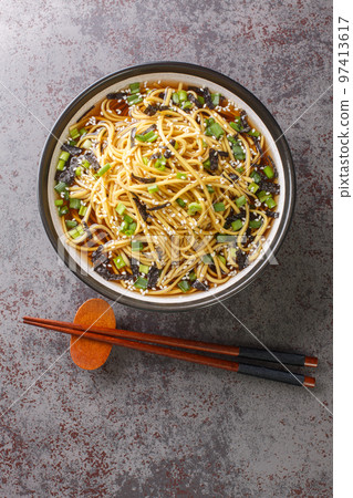 Memil guksu is a traditional South Korean soba noodle soup with green onions and seaweed closeup in the bowl. Vertical top view Memil guksu is a traditional South Korean soba noodle soup with green onions and seaweed closeup in the bowl. Vertical top view 97413617