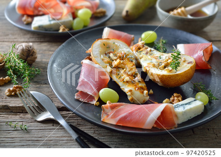 Baked pears stuffed with gorgonzola blue cheese, served with walnuts and South Tyrolean bacon 97420525