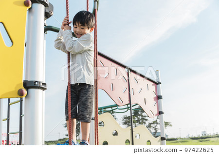 5 year old boy playing on playground equipment 97422625