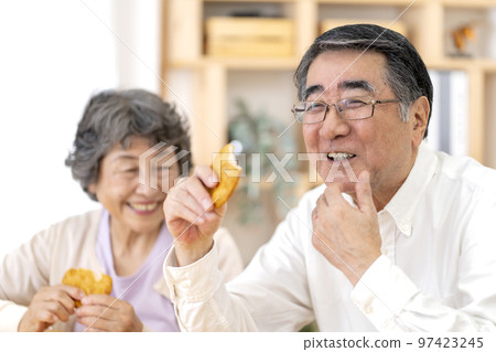 Senior couple eating rice crackers 97423245