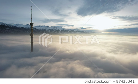 The TV tower looks out of the clouds at sunset. 97423341