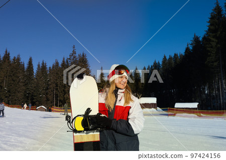 Young woman with ski mask holding snowboard outdoor 97424156