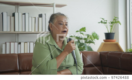 Holiday concept of 4k Resolution. Asian old woman having fun practicing singing at home. Holiday concept of 4k Resolution. Asian old woman having fun practicing singing at home. 97426488