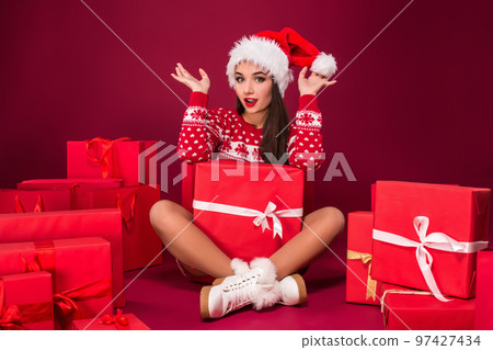 Young Caucasian woman is sitting on the floor surrounded by shopping bags and Christmas gifts. 97427434