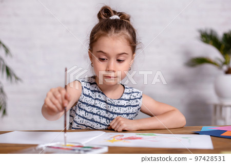 Inspired little girl at the table draw with paints 97428531